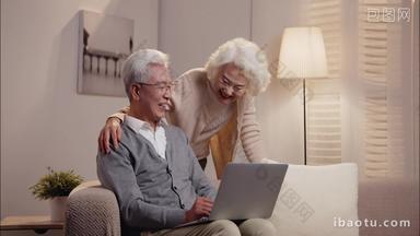 老年夫妇<strong>坐</strong>在<strong>沙发上</strong>使用笔记本电脑